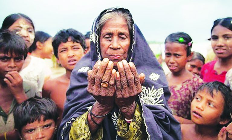 Rohingya Muslim woman prays for relief from oppression as children look on.
